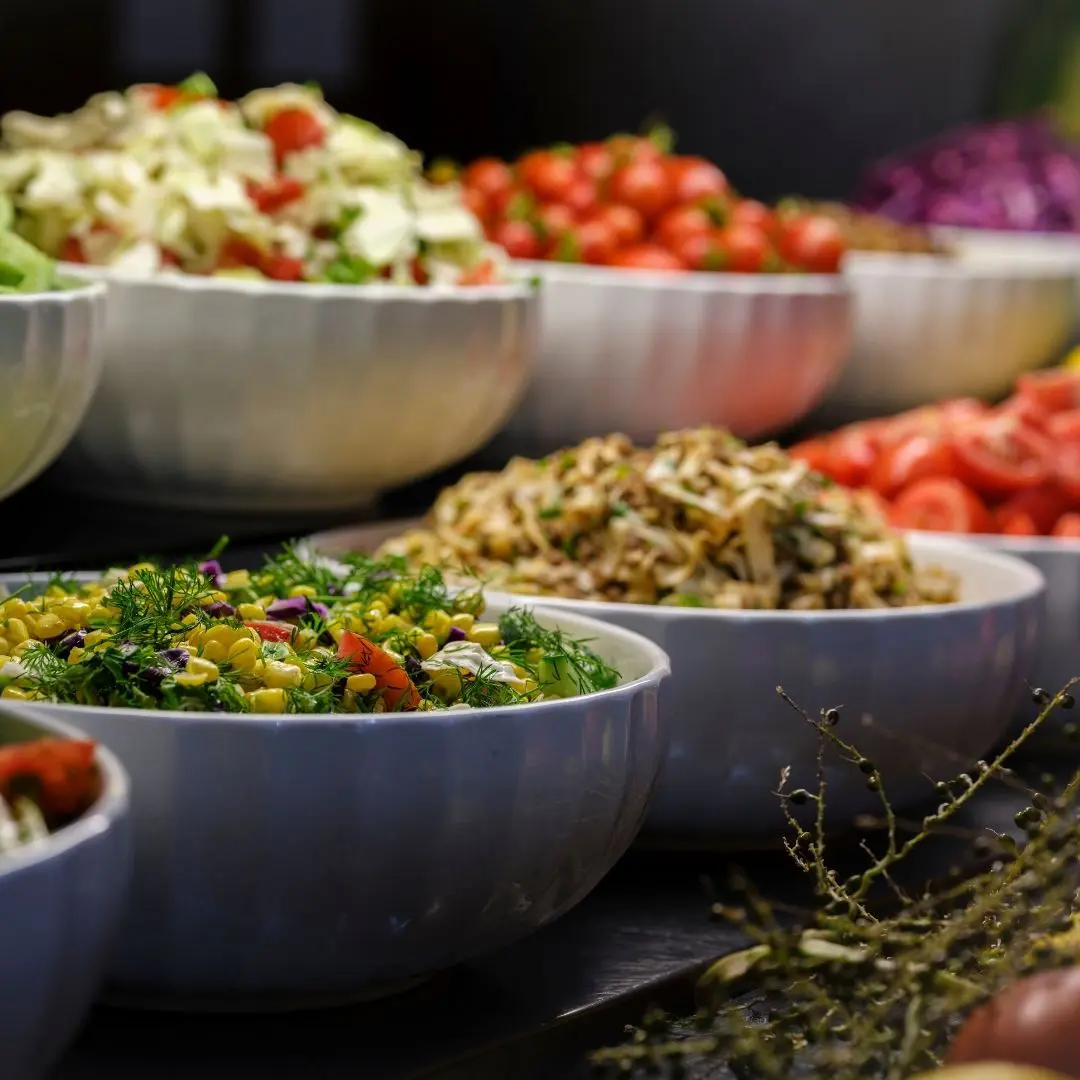 Catering beim westand Braunschweig: verschiedene appetitliche Salate sind in weißen Schalen auf einem Buffet aufgebaut.