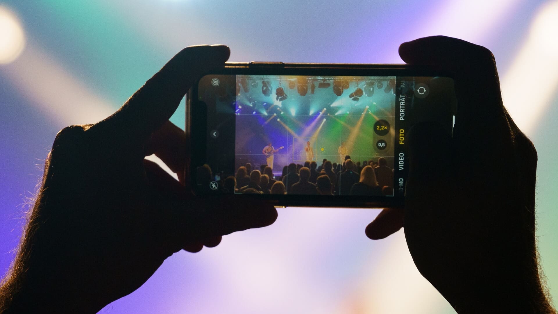 Hände, die ein Smartphone halten und ein Foto von der Bühne im westand Braunschweig während eines Konzerts aufnehmen.